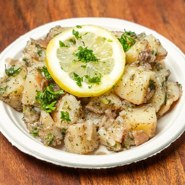 Hovan Gourmet Mediterranean potato salad with herbs and a lemon slice on a white plate.