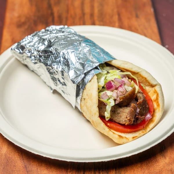 Hovan Gourmet Mediterranean gyro wrap with meat, lettuce, tomatoes, and onions, partially wrapped in foil.